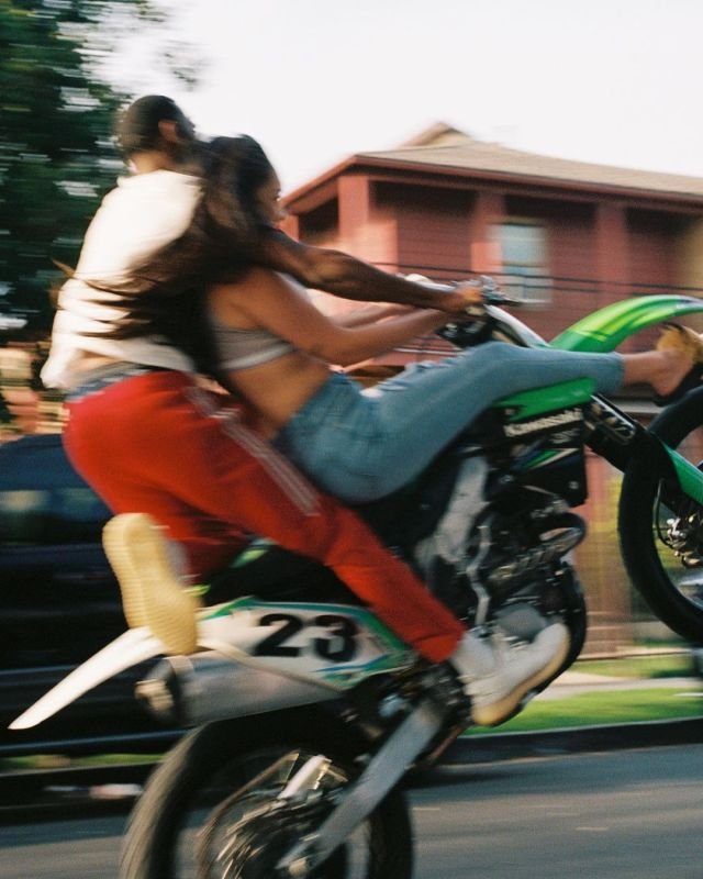 Dos personas en una moto haciendo un caballito